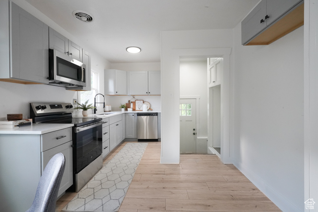 Kitchen with stainless steel appliances, a sink, plenty of natural light, and light wood-style flooring