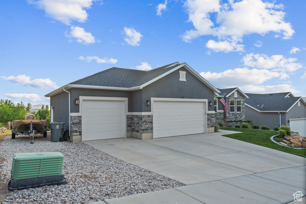View of front of house with stone siding, an attached garage, concrete driveway, and stucco siding