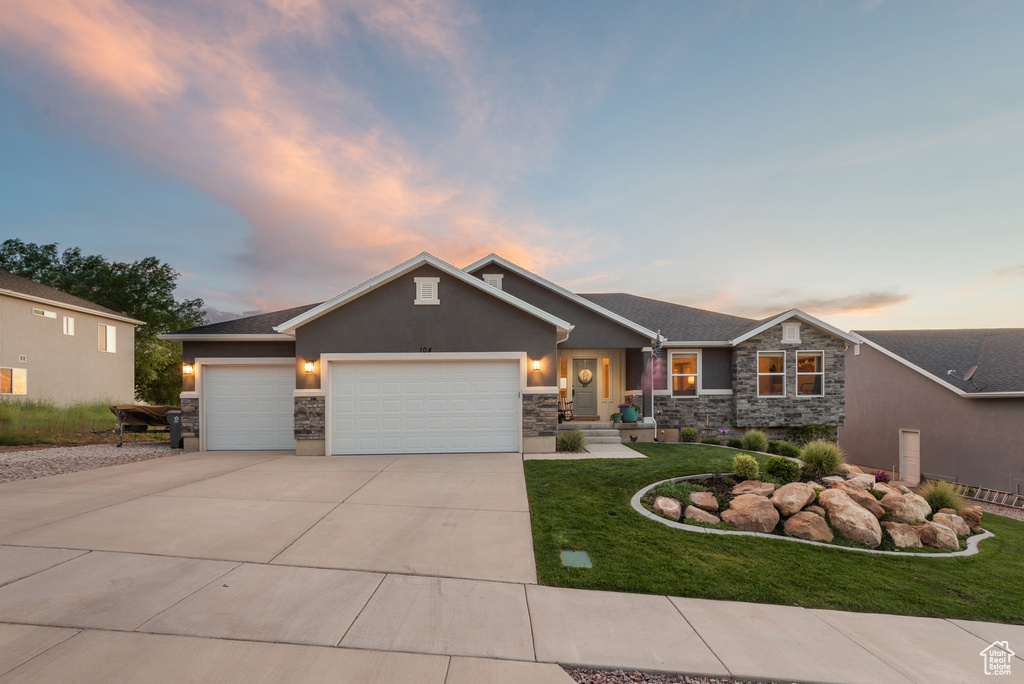 Craftsman-style house featuring an attached garage, stone siding, stucco siding, concrete driveway, and a front lawn