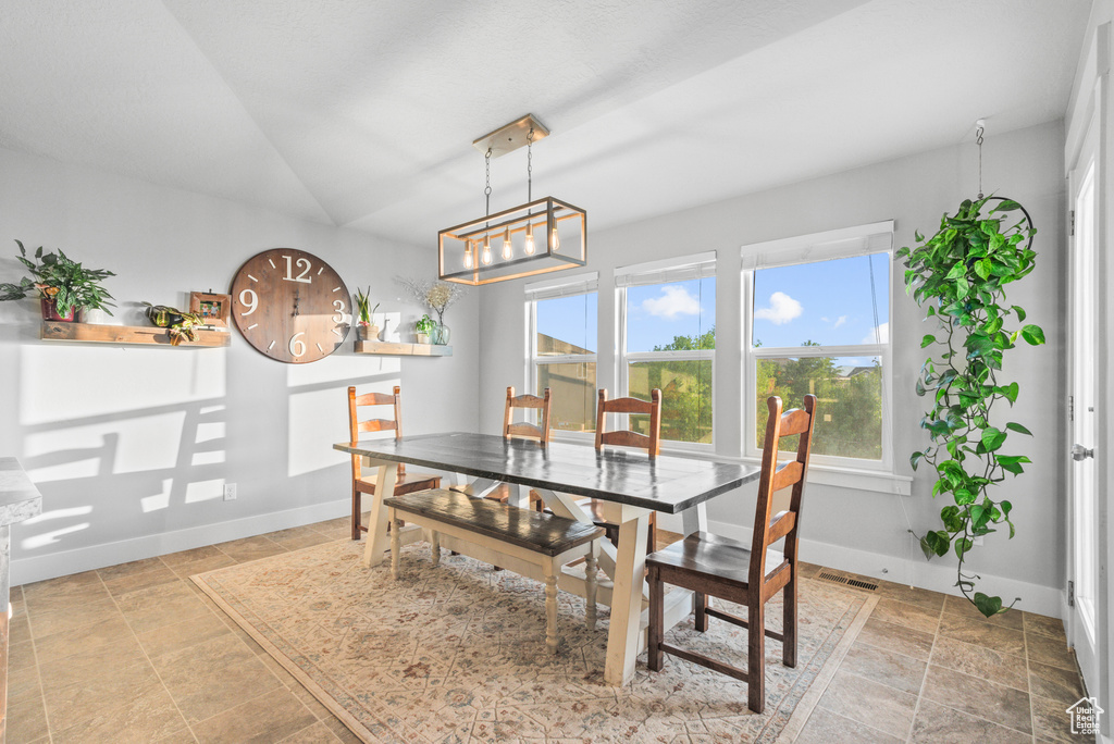 Dining room with baseboards, a chandelier, light stone finish floors, and lofted ceiling