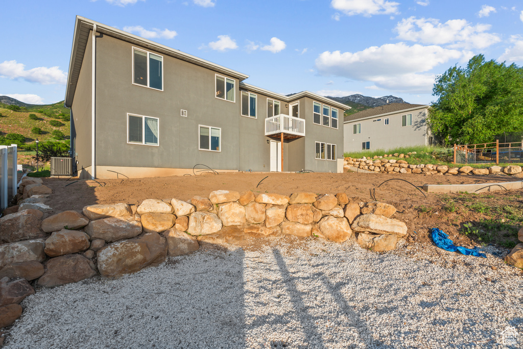 Rear view of property featuring central AC unit, a mountain view, a balcony, stucco siding, and a patio area