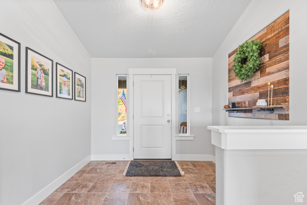 Entryway featuring baseboards, a textured ceiling, and stone finish flooring