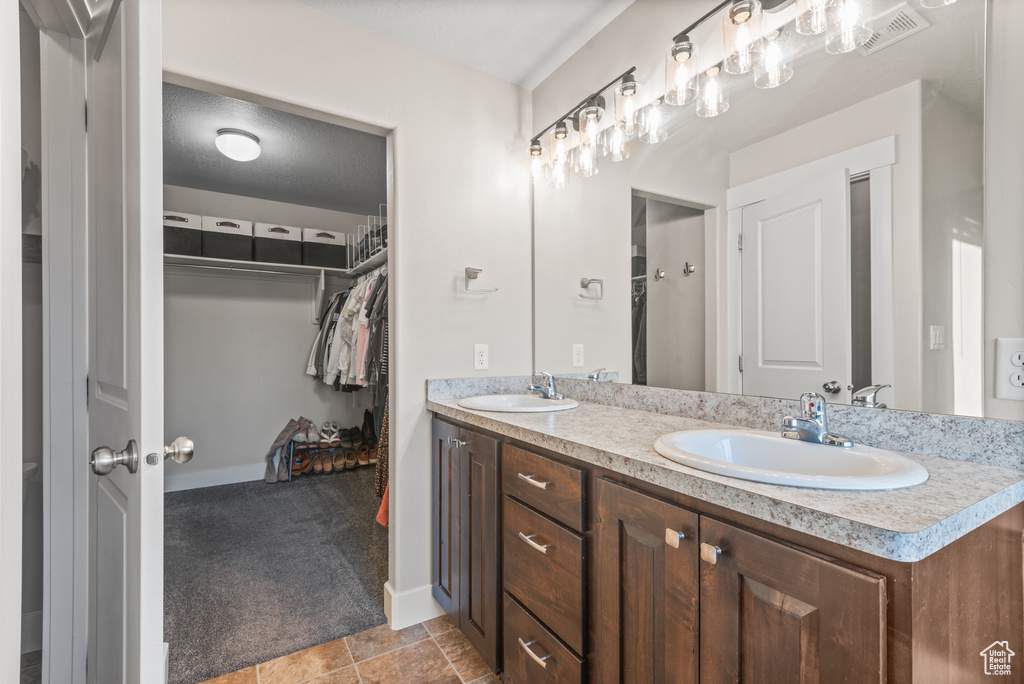 Full bathroom featuring double vanity, a spacious closet, and baseboards