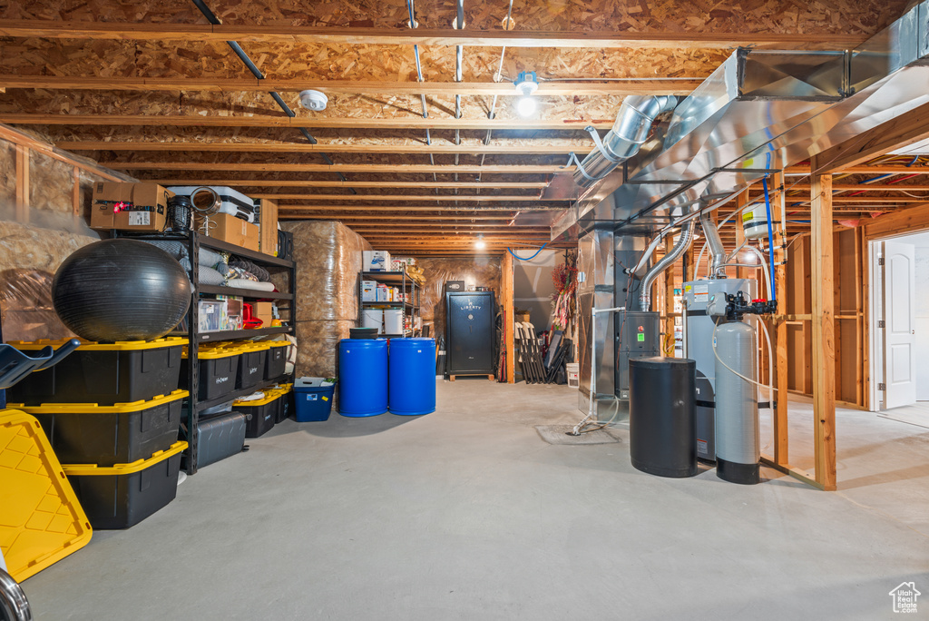 Unfinished below grade area featuring heating unit and a water softener system