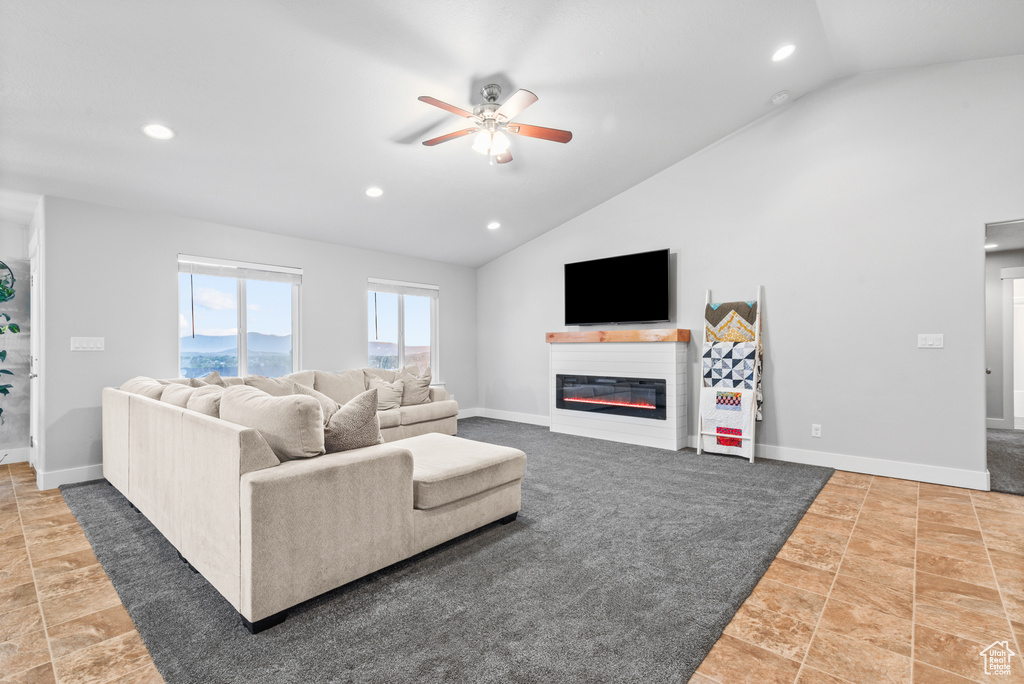 Living room with a ceiling fan, a glass covered fireplace, recessed lighting, high vaulted ceiling, and baseboards