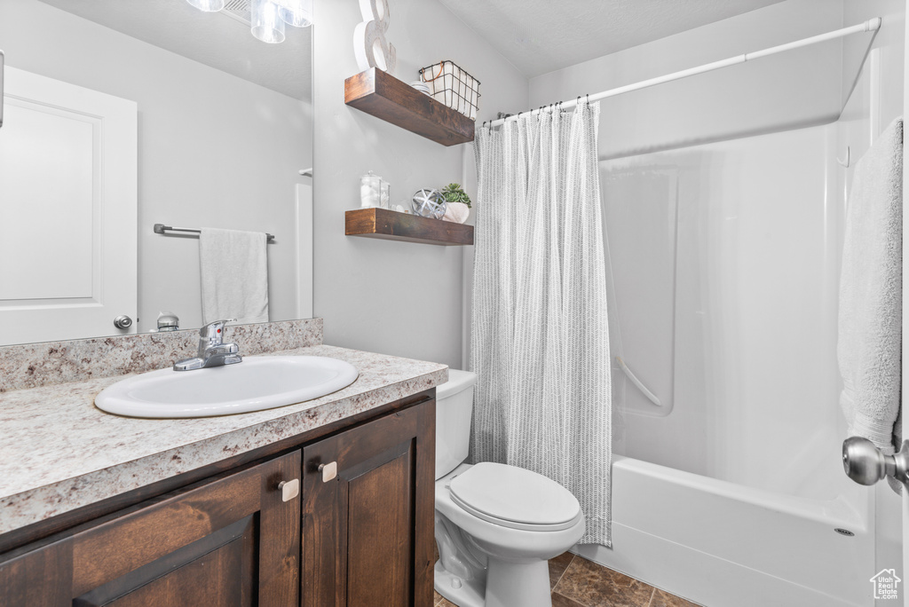 Full bathroom with toilet, vanity, and shower / bath combo