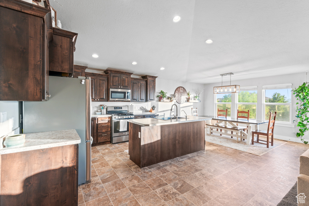 Kitchen featuring appliances with stainless steel finishes, light countertops, a sink, dark brown cabinetry, and recessed lighting