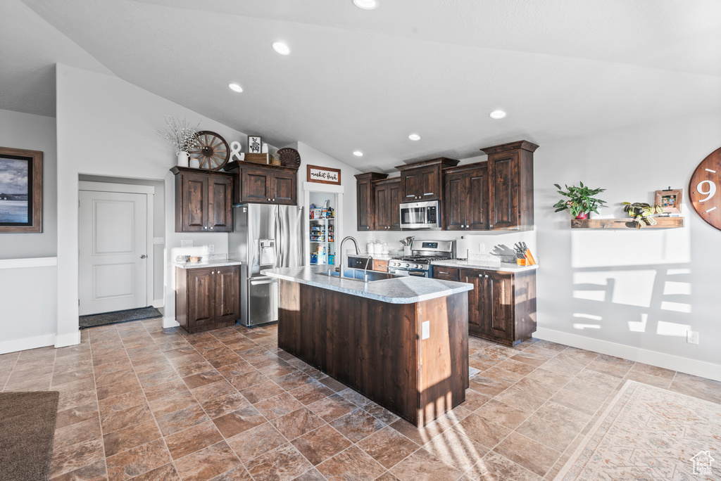 Kitchen featuring stainless steel appliances, dark brown cabinets, baseboards, light countertops, and lofted ceiling