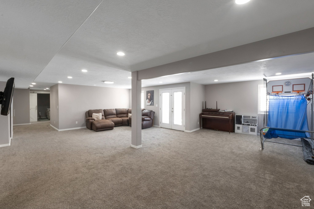 Basement with recessed lighting, carpet, baseboards, a textured ceiling, and french doors