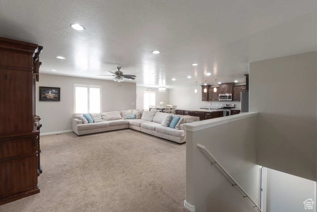 Living area with recessed lighting, light carpet, a ceiling fan, and baseboards
