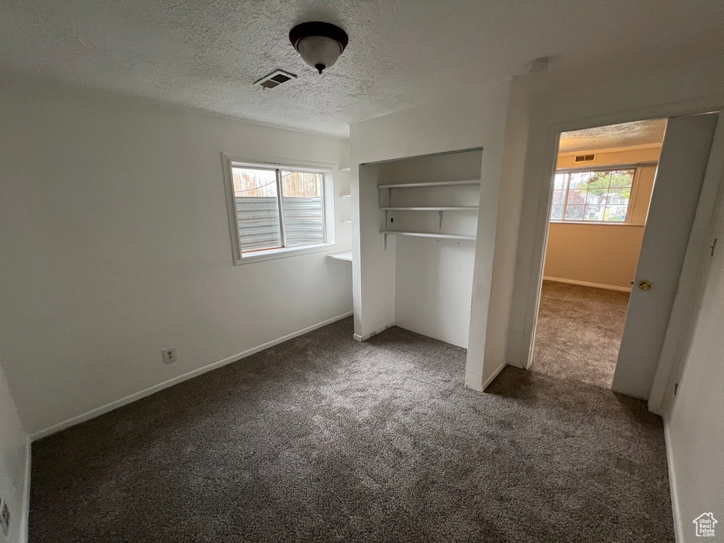 Unfurnished bedroom featuring carpet floors, a textured ceiling, a closet, and baseboards