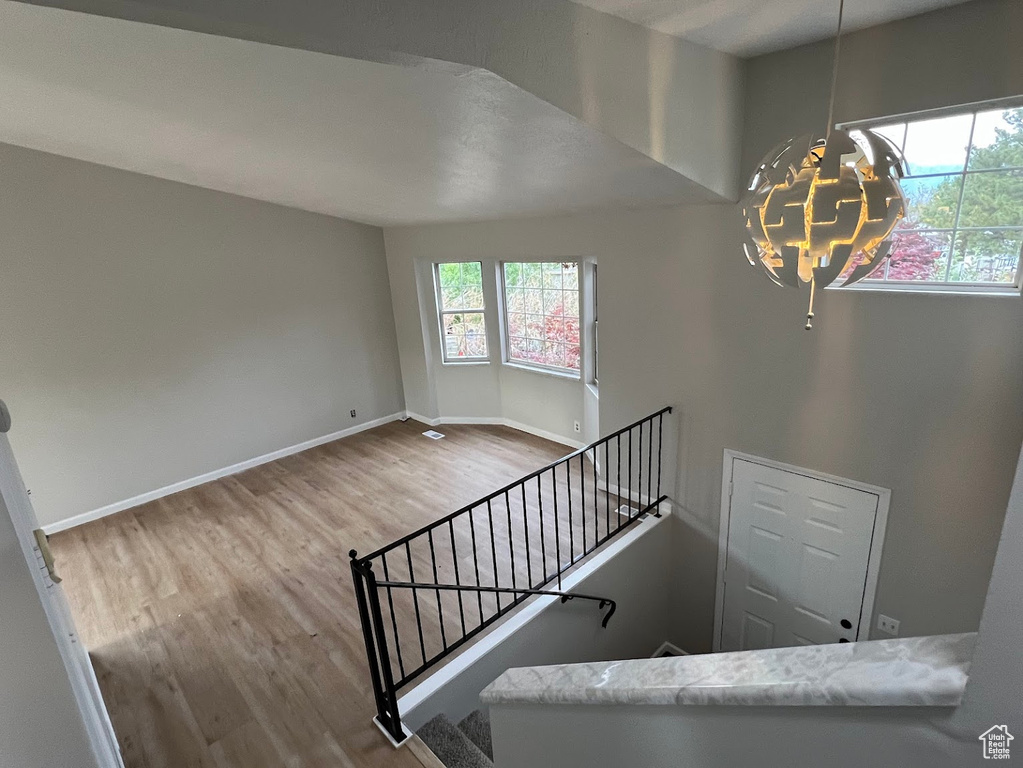 Staircase with wood finished floors, a chandelier, and baseboards