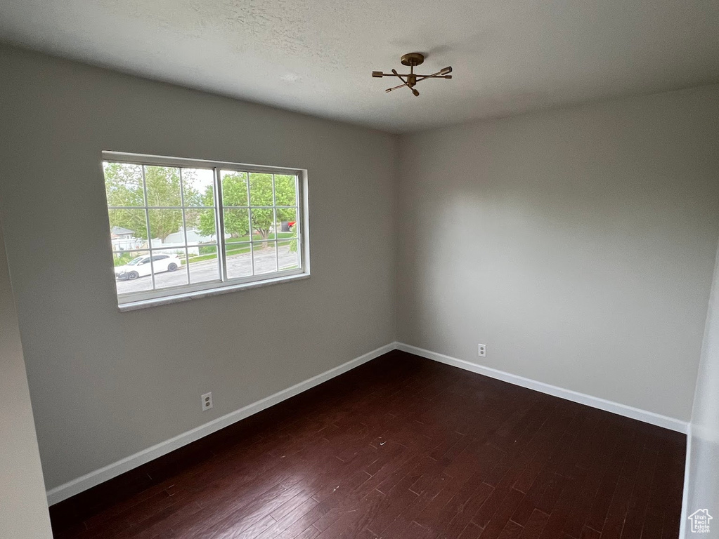 Unfurnished room featuring baseboards and dark wood-style floors