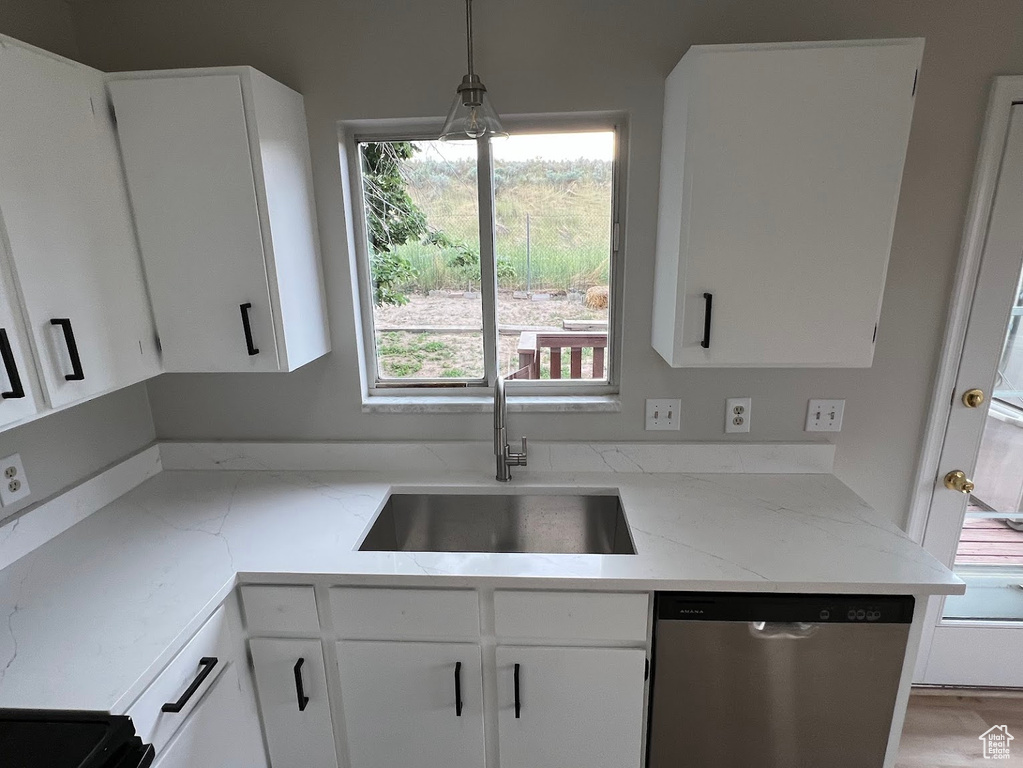 Kitchen featuring stainless steel dishwasher, a sink, and white cabinets
