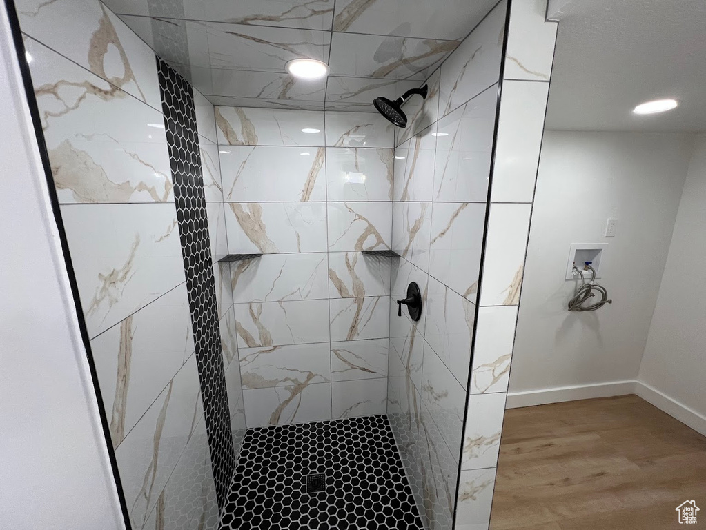 Full bathroom with tiled shower, wood finished floors, and baseboards