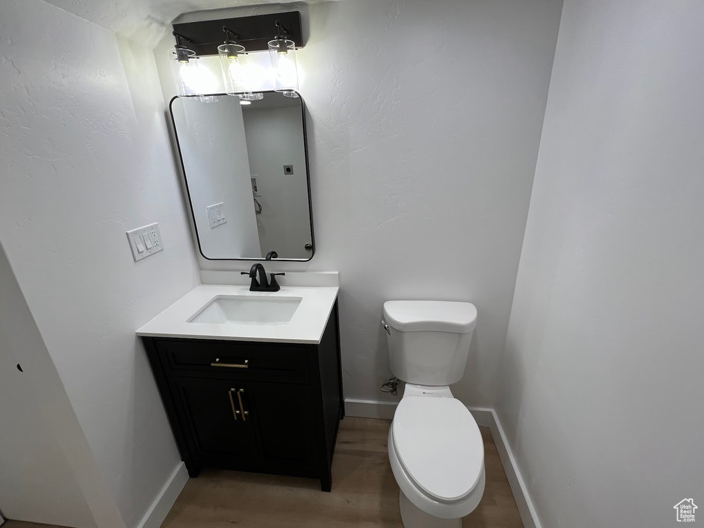 Bathroom featuring toilet, vanity, baseboards, and wood finished floors