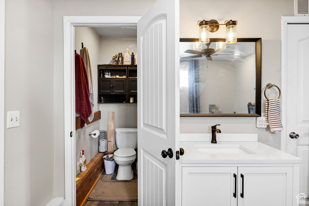Bathroom with toilet, vanity, and a ceiling fan
