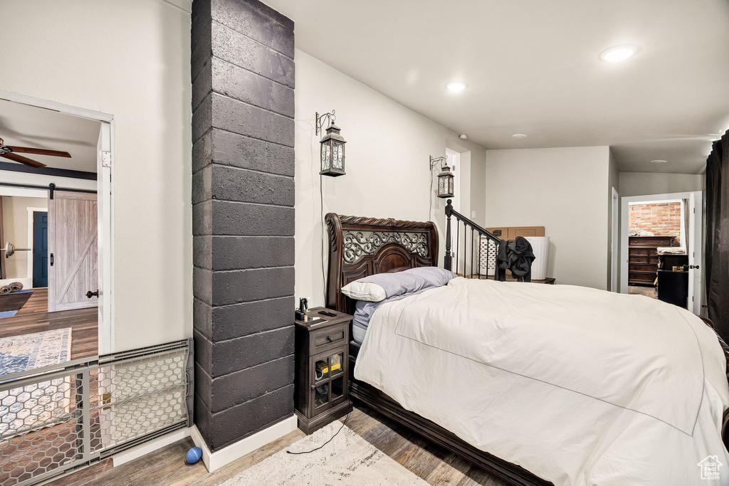 Bedroom with wood finished floors, a barn door, and recessed lighting
