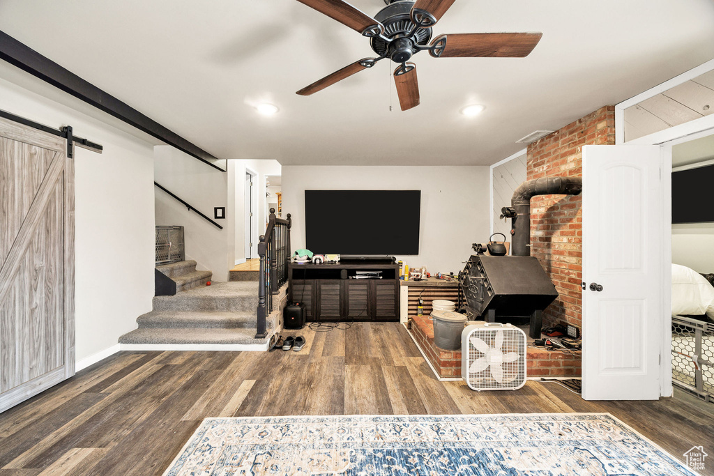 Living room with wood finished floors, stairs, a barn door, ceiling fan, and recessed lighting
