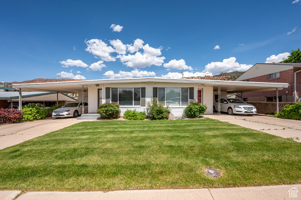Manufactured / mobile home featuring a carport, driveway, and a front yard