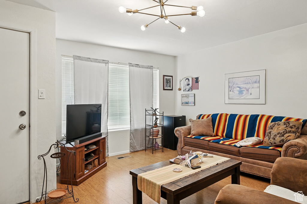 Living room featuring a chandelier, light wood-type flooring, and baseboards