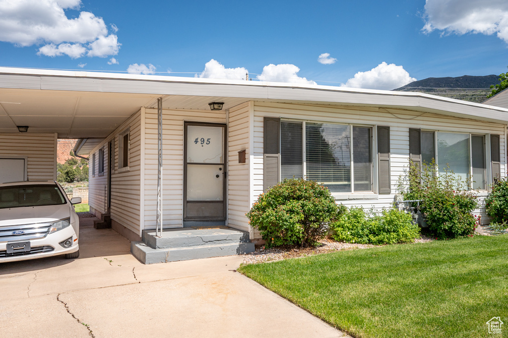 Property entrance featuring a carport, a lawn, and concrete driveway