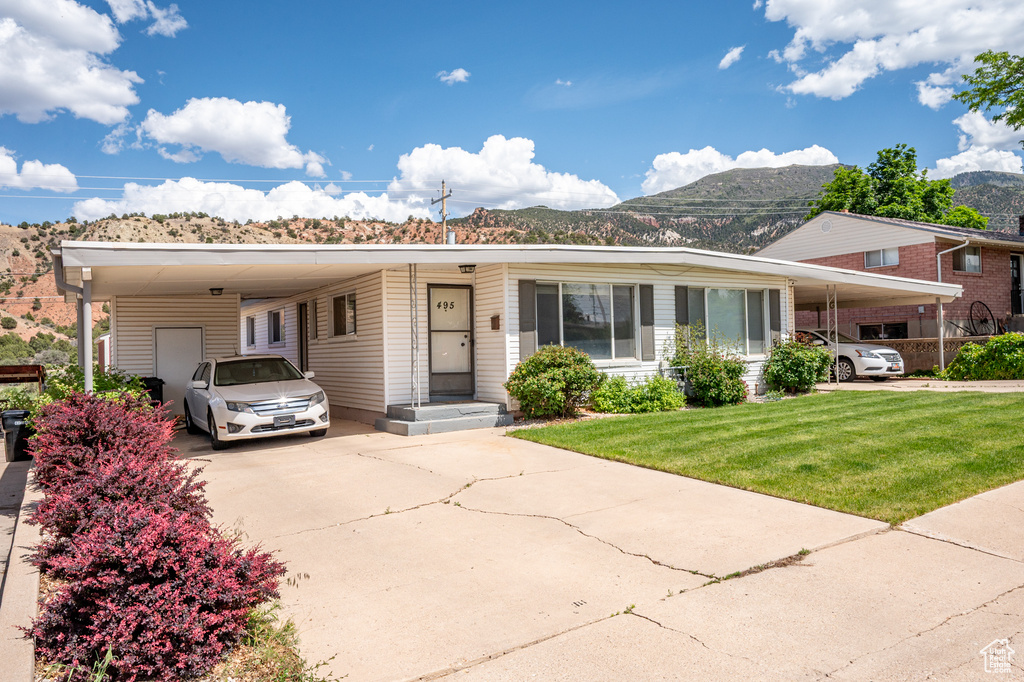 Manufactured / mobile home with a mountain view, a carport, concrete driveway, and a front yard
