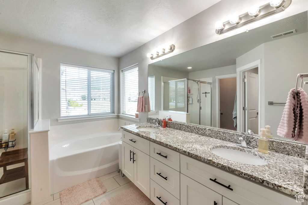 Full bath with a shower stall, double vanity, a garden tub, and tile patterned flooring