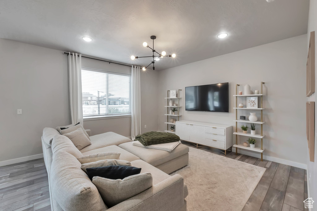 Living area featuring a chandelier, wood finished floors, baseboards, and recessed lighting