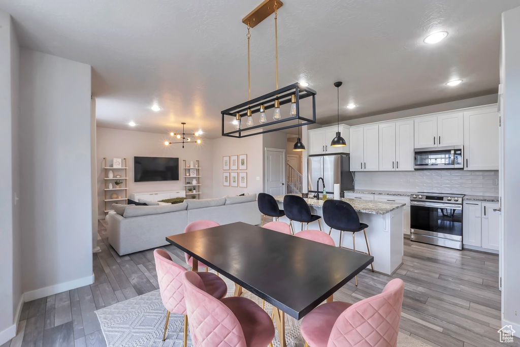 Dining area with light wood-style floors, baseboards, recessed lighting, and a chandelier