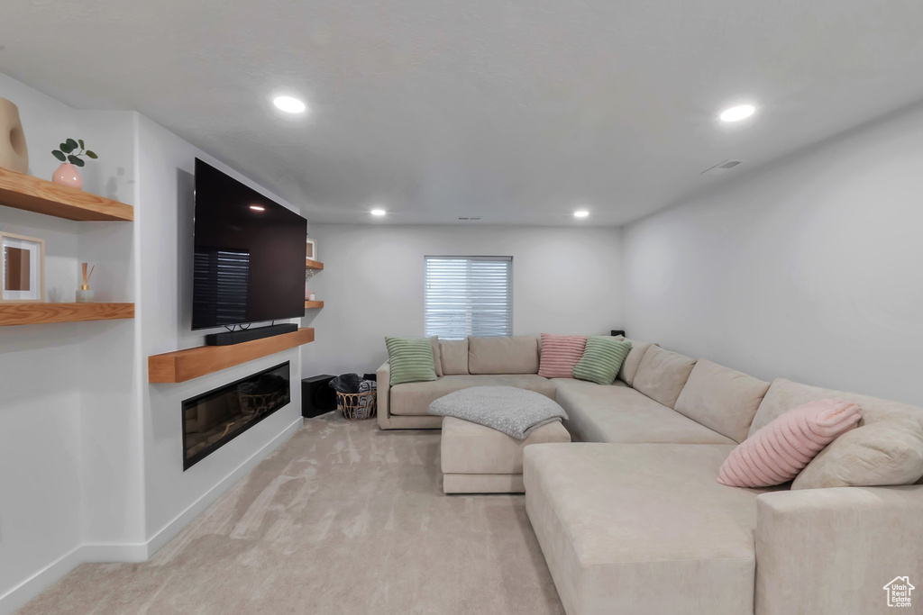 Living room with light colored carpet, a glass covered fireplace, and recessed lighting