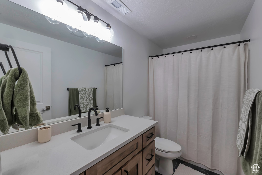 Full bathroom with toilet, vanity, and tile patterned flooring