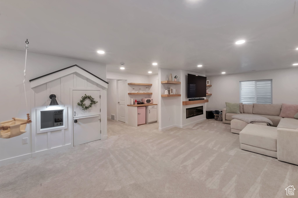Living area featuring light colored carpet, a glass covered fireplace, recessed lighting, and baseboards