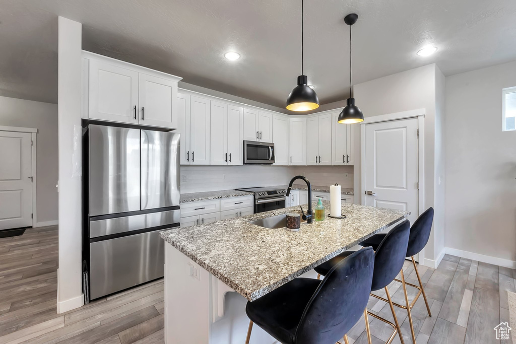 Kitchen with appliances with stainless steel finishes, a sink, baseboards, light stone counters, and recessed lighting