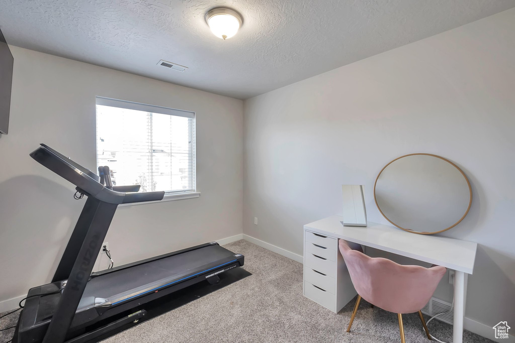 Workout area with a textured ceiling, baseboards, and light carpet