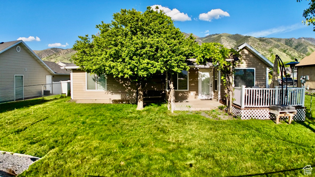 Rear view of house featuring a deck with mountain view and a patio area