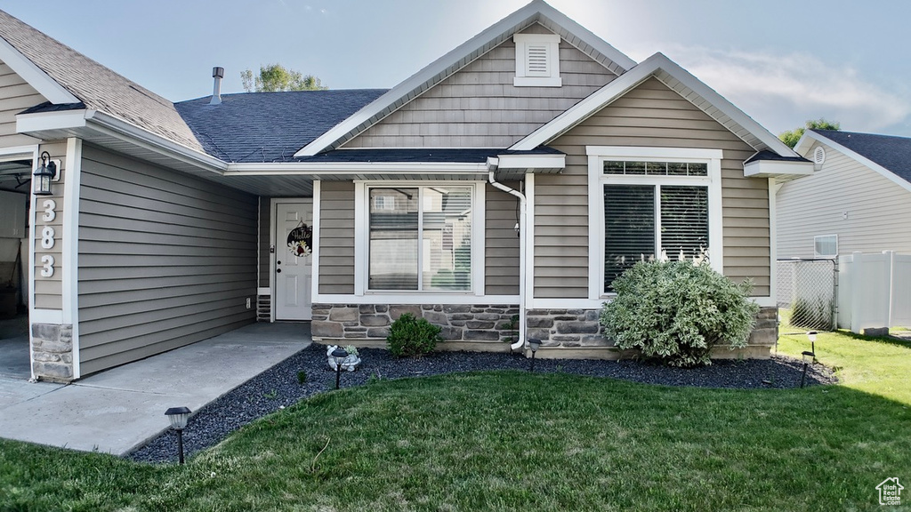 View of front facade featuring stone siding and roof with shingles