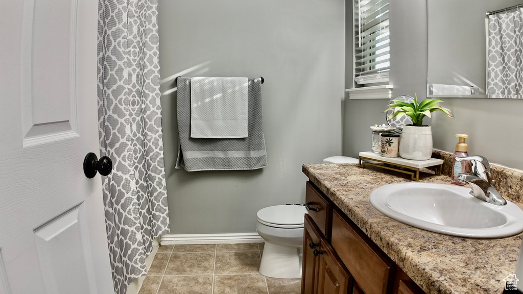 Full bathroom featuring vanity, toilet, baseboards, and tile patterned floors