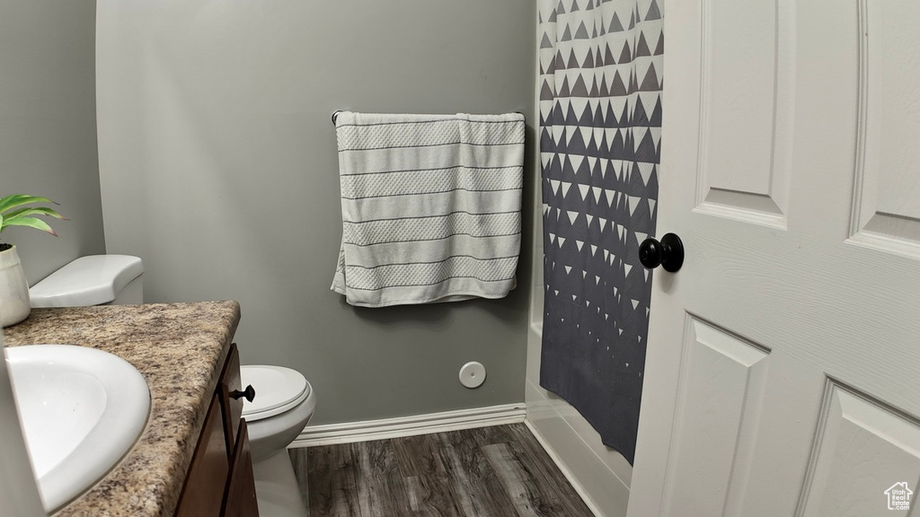 Full bathroom featuring toilet, wood finished floors, vanity, a shower with curtain, and baseboards