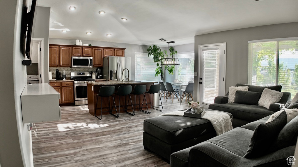 Living area featuring healthy amount of natural light, light wood-style floors, a chandelier, and recessed lighting
