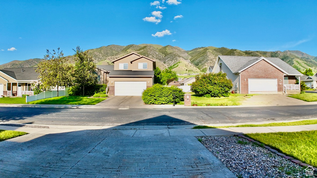 View of front facade featuring a mountain view, decorative driveway, a residential view, and brick siding