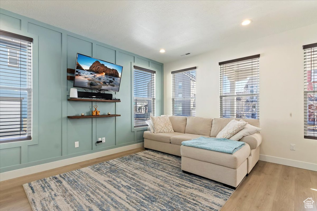 Living area with light wood-style floors, baseboards, and recessed lighting