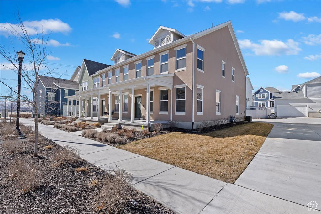 View of front of house featuring a porch, a residential view, a front lawn, and stucco siding