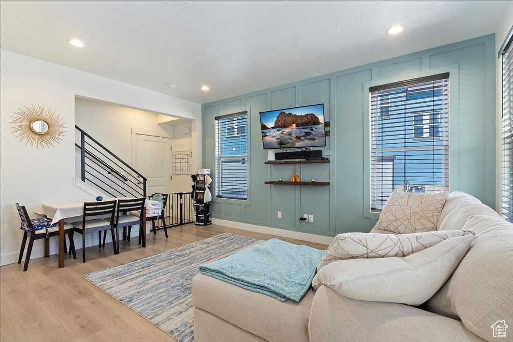 Living area with light wood-type flooring, stairs, baseboards, a decorative wall, and recessed lighting