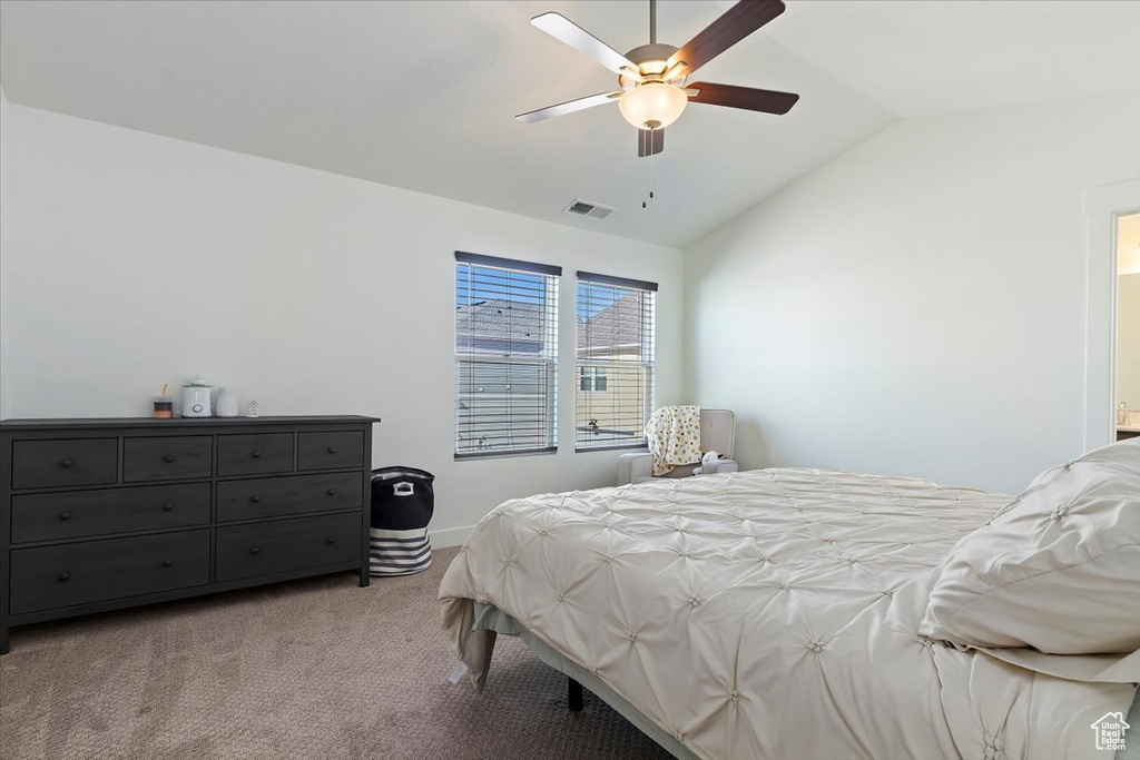 Bedroom with vaulted ceiling, carpet flooring, baseboards, and ceiling fan