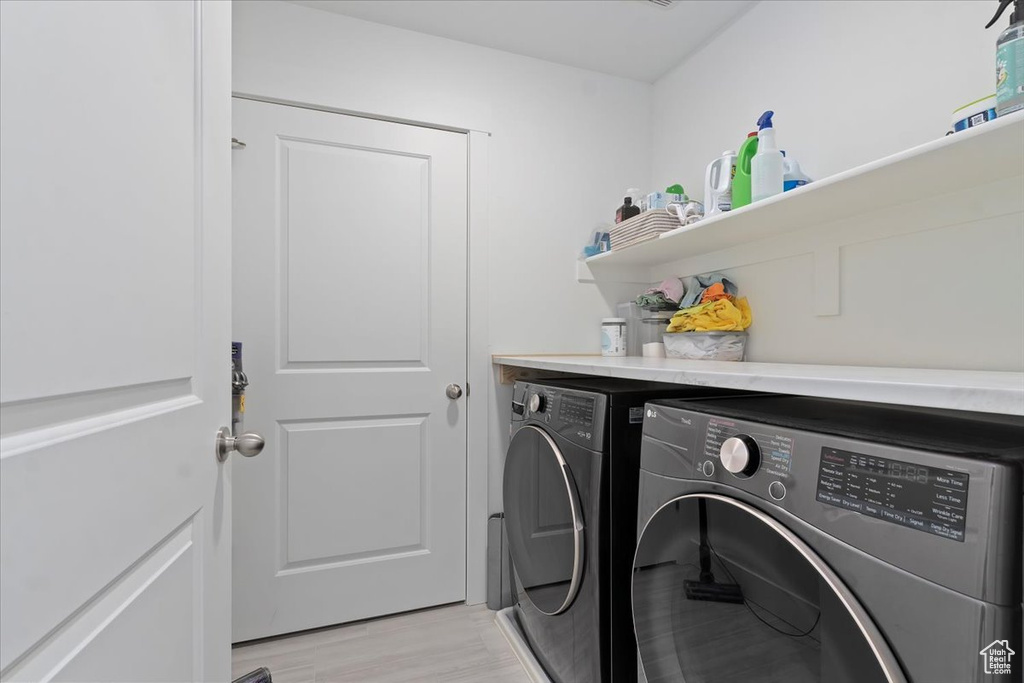 Laundry area with washing machine and clothes dryer and light wood finished floors