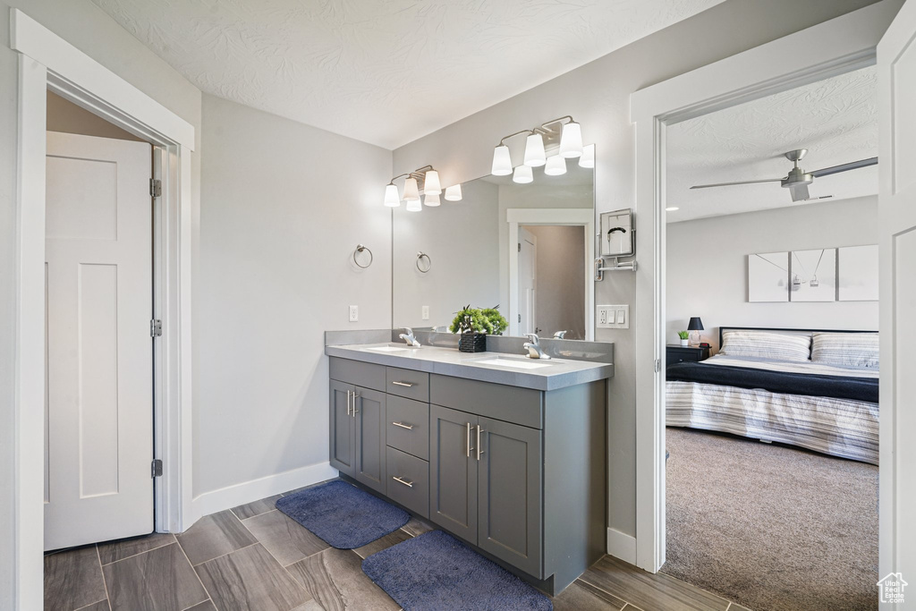 Full bath featuring ensuite bathroom, double vanity, baseboards, a textured ceiling, and wood tiled floors