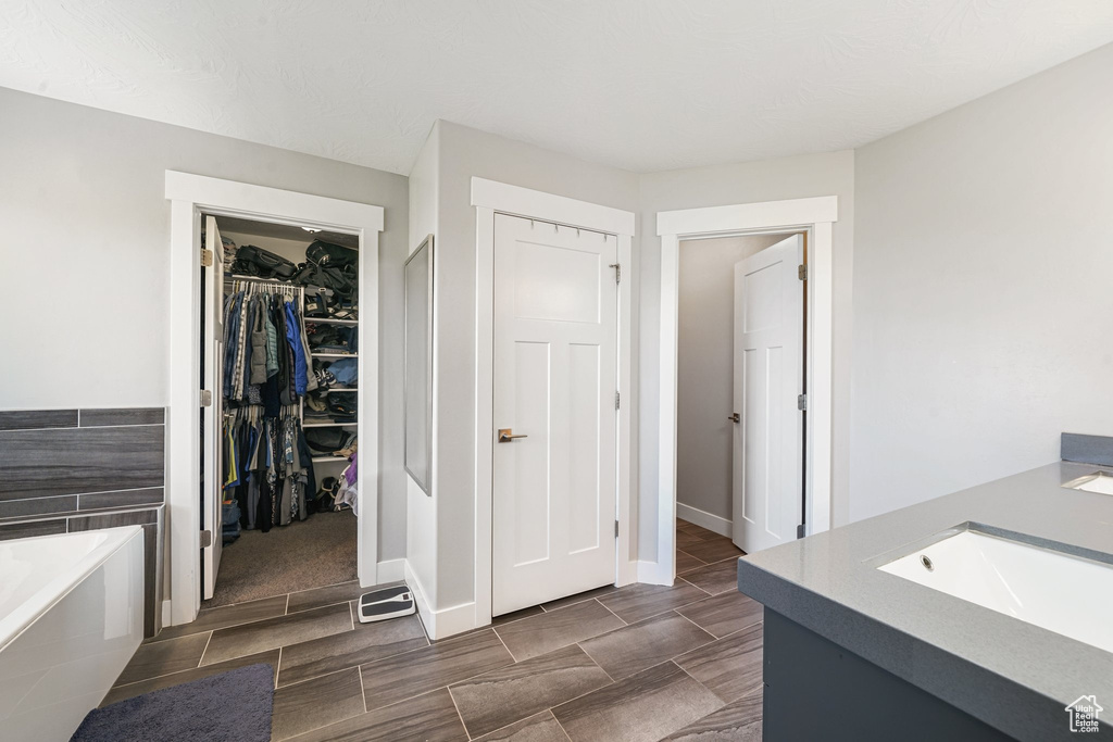 Bathroom featuring a bath, vanity, and a walk in closet