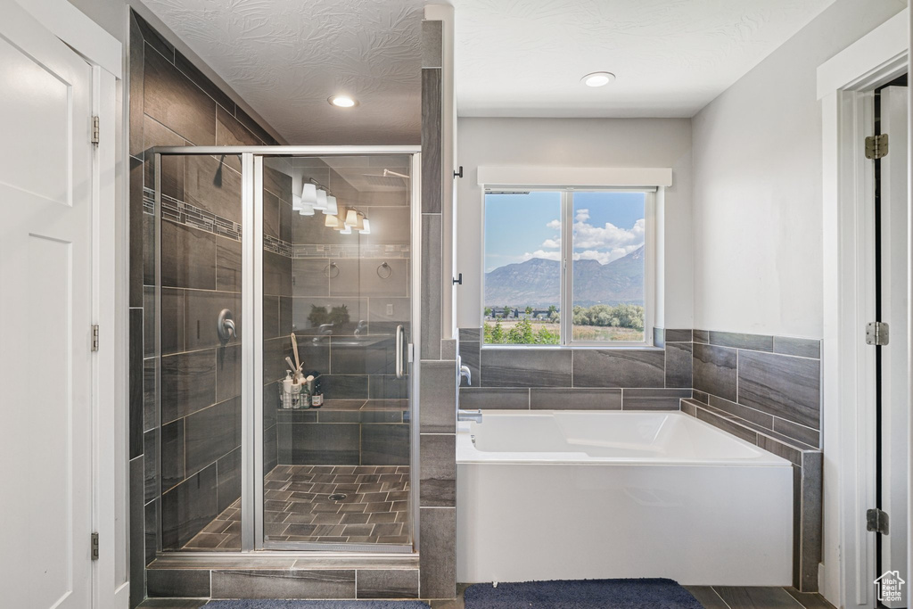 Full bathroom featuring a bath, a stall shower, recessed lighting, a mountain view, and tile walls