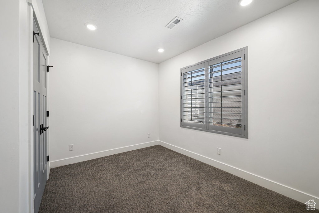 Spare room featuring dark carpet, baseboards, and recessed lighting